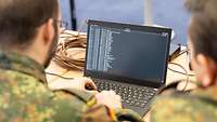 Zwei Soldaten schauen auf einen Laptop.