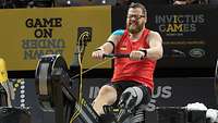 Ein Soldat mit Beinprothese in Sportbekleidung auf der Rudermaschine bei den Invictus Games