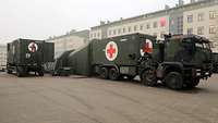 Rettungsstation der Sanitätskräfte An einem Militärlastkraftwagen der Sanitätskräfte ist am Heck ein Zelt angebaut, links davon steht ein Stromaggregat.