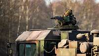 Ein Soldat schießt mit einem Maschinengewehr aus der Luke eines Fahrzeuges.