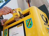 Feldpost Eine Hand steckt eine Postkarte in einen Briefkasten