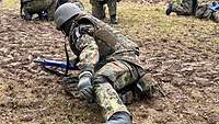 Ein Soldat kriecht mit einer simulierten Beinwunde in die Richtung seiner Kameraden.