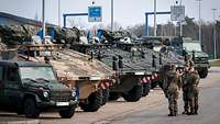 Soldaten stehen mit ihren Fahrzeugen auf einem großen Autobahnrastplatz an der polnischen Grenze.