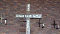 Kreuz mit der Aufschrift Friede, Jesus, Peace, Pace, Mir