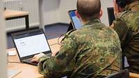 Zwei Teilnehmende des deutschen Teams sitzen vor ihren Computern.