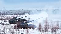 Drei Panzerhaubitzen 2000 schießen nebeneinander im Schnee. 