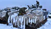 Fahrzeuge in der Wintertarnung Soldaten befestigen Material zur (Winter-)Tarnung an einem SPz Marder.