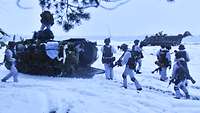 Norwegische Infanterie am Werk Infanteristen sitzen auf einer verschneiten Fläche von ihrem M113 ab.