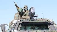 Ein Soldat steht in einer Luke des Transportpanzers Fuchs an seinem Maschinengewehr.