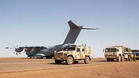 Ein Flugzeug vom Typ A400M steht am Flughafen Gao. Am Flugfeld parken ein Eagle und Lastkraftwagen.
