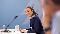 Soldatin in Luftwaffenuniform sitzt an einem Tisch vor einem Mikrofon