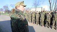 Eine Soldatin steht vor einer Gruppe angetretener Soldaten