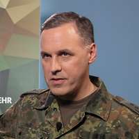 Ein Soldat steht vor einem Monitor während eines Interviews mit einem anderen Soldaten.