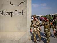 Das Team aus Soldaten läuft entlang einer hohen Betonmauer, auf der „MN Camp Erbil“ steht