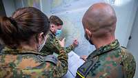 Zwei Soldaten besprechen sich vor einer Mali-Karte, während ein Soldat etwas mit dem Stift einzeichnet
