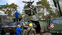 Der Motor eines Transportpanzers wird mittels Kran aus dem Chassis gehoben