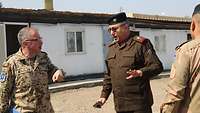 Ein deutscher Soldat im Gespräch mit einem irakischen General. Ein weiterer irakischer Soldat folgt den Ausführungen. 