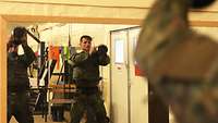 Zwei Soldaten schwingen Gewichte, sogenannte Dumbbells, vor einem Spiegel.