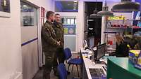 Bei der Beschaffung Zwei Soldaten stehen im Verkaufsraum einer Werkstatt.