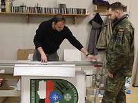 deutsch-polnische Zusammenarbeit Ein Soldat neben einem Zivilisten, der an einem Papier arbeitet.