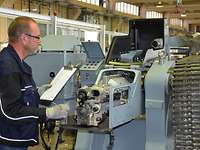 Marinearsenal Marineleichtgeschütz Ein Mann in blauer Arbeitsjacke steht am Verschluss eines Geschützes auf einer grauen Lafette.