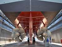 Marinearsenal Fregatte Bayern Das Heck eines grauen Schiffs in einem Dock; zu sehen sind die beiden Schiffspropeller und das Ruder.