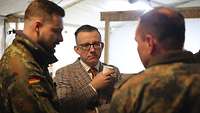 Ein Soldat und ein Zivilist unterhalten sich. Ein weiterer Soldat steht neben ihnen und dolmetscht das Gespräch.