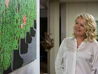 Eine Frau blickt zur Seite auf ein Bild mit Beinen von Soldaten mit einer Kinderhand mit Lolli
