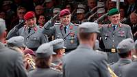 Ein Soldat überreicht einem anderen Soldaten eine Truppenfahne während eines Appells.