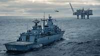 Fregatte „Mecklenburg-Vorpommern“ bei SNMG1 Ein Kriegsschiff fährt auf hoher See vor einer Bohrplattform