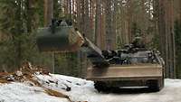 Ein Pionierpanzer Dachs mit ausgefahrenem Baggerarm im verschneiten Wald