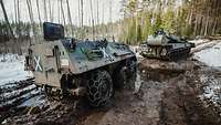 Ein Pionierpanzer Dachs schleppt einen Transportpanzer Fuchs auf einem schlammigen Waldweg ab