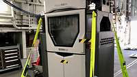 großer Drucker befestigt mit Gurten im Hangar eines Schiffes