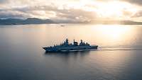 Ein Schiff fährt bei Sonnenschein zwischen den Fjorden entlang.