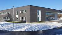 Parkplatz und ein zweigeschossiges Gebäude mit Flachdach und einem verglasten Eingangsbereich