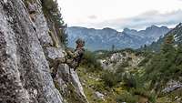 Ein Soldat hängt an einem Seil in einer Felswand im alpinen Gebirge.