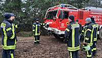 Feuerwehrmänner stehen im Schneeregen vor einem Feuerwehrfahrzeug 