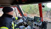 Ein Fahrerhaus eines Lkw von Innen. Ein Feuerwehrmann am Steuer.