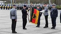 Der Inspekteur CIR bringt das Fahnenband an die Truppenflagge des Kommandos IT-Services der Bundeswehr