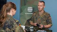 Ein Soldat und eine Soldatin stehen sich gegenüber und sprechen miteinander.
