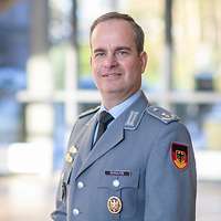 Portraitbild von Oberstleutnant Schultze vor einem Gebäude.