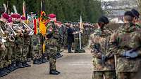Vor einem Schloss im Hofgarten stehen zahlreiche Soldaten und Musiker in Formation.