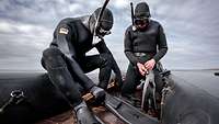 Zwei Männer in schwarzen Tauchanzügen, mit Schnorchel und Tauchmaske in einem schwarzen Gummiboot