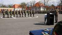Elf Soldaten stehen auf einem Antreteplatz. Im Vordergrund liegen die Waldbrandmedaillen