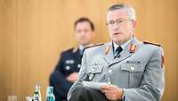 Ein Soldat sitz auf einem Stuhl und spricht mit anderen Vortragenden