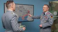 Zwei Soldaten sprechen miteinander vor einem Monitor, auf dem einen Ukraine-Karte zu sehen ist.