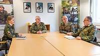 Drei Soldaten und eine Soldatin an einem Tisch. Ein Soldat redet, die anderen hören interessiert zu