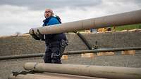 A soldier lifts a heavy pipeline pipe