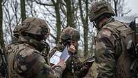 Soldaten in französischer Uniform stehen zusammen, eine Soldatin telefoniert.