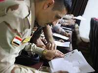 Mehrere irakische Soldaten sitzen in einem Klassenraum. Sie alle haben ein Blatt Papier vor sich.